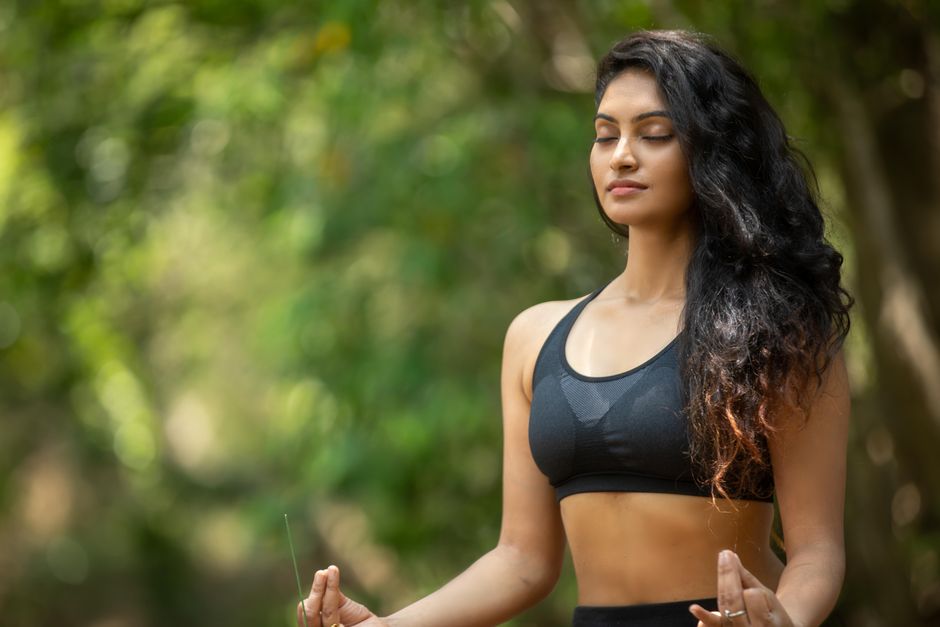 Mulher de meia-idade respirando profundamente com os olhos fechados em ambiente calmo para controlar ansiedade