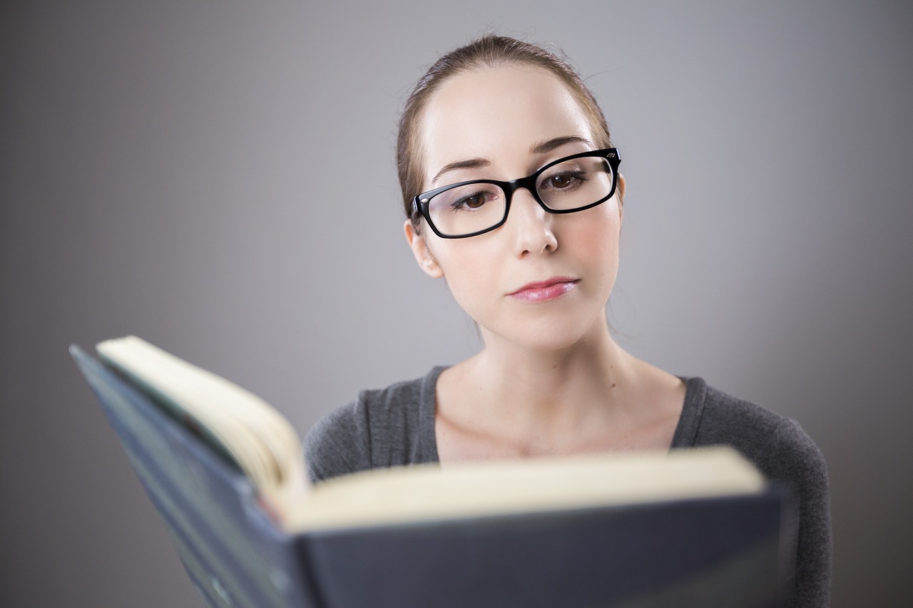 Mulher usando óculos de leitura para ler livro com conforto visual