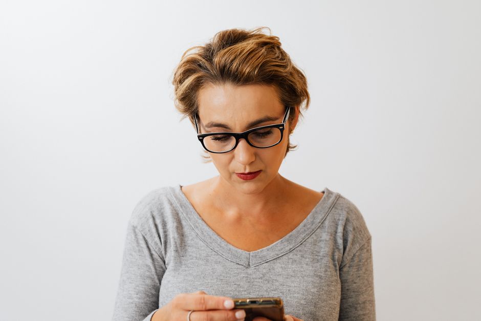 Mulher afastando o celular para conseguir ler melhor, sinal típico de presbiopia